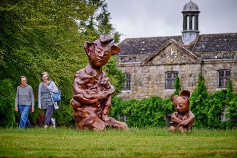 Two women looking at abstract sculpture of humans